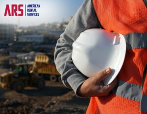 A construction worker in the foreground, holding a hard hat. Construction equipment in the background with the logo ARS, American Rental Services